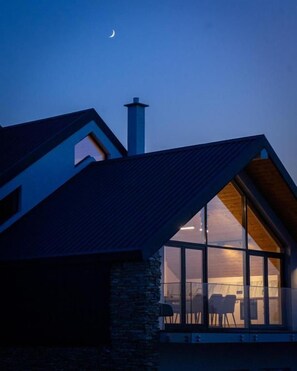 Un edificio moderno con techo inclinado, ventanas grandes y una chimenea.