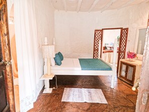 Ein kleines, gemütliches Schlafzimmer mit einem Bett, einem Nachttisch, einer Lampe und einem Spiegel.