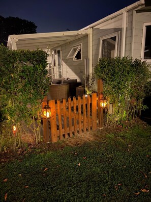 A white house with a wooden fence, a porch, and a garden area at night. - Chalet Lebensfreude – A Getaway by the Water (Lathum)