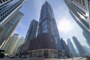 A high-rise building with a modern architectural design, surrounded by other tall buildings. - Cozy 1 Bed Perched on 52nd Floor l Marina Walk (Dubai Marina)