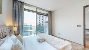 Een moderne hotelkamer met een groot bed, uitzicht over de stad en een balkon.