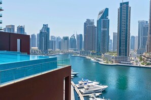 A high-rise building with a rooftop pool overlooking a marina with boats. - Cozy 1 Bed Perched on 52nd Floor l Marina Walk (Dubai Marina)