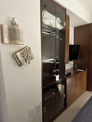 Ein modernes Schlafzimmer mit Kleiderschrank, Flachbildfernseher und dekorativen Elementen an der Wand.