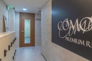 Un couloir avec une plaque sur le mur indiquant « CHAMBRE PREMIUM COMO » et une porte portant l’inscription « Cuisine ».