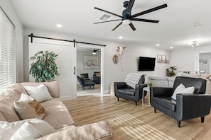 Ein modernes Wohnzimmer mit Deckenventilator, Sofa, Couchtisch und Fernseher.