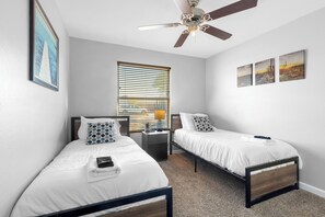 A bedroom with two single beds, a ceiling fan, a window with blinds, and artwork on the wall. - Sleeps 12, Private Pool,BBQ (Tempe)