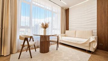 A modern living room with a sofa, two chairs, a coffee table, and a large window with curtains.