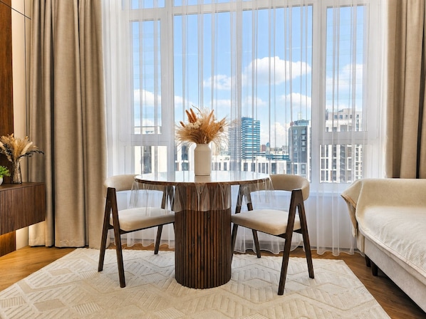 Un dormitorio moderno con un ventanal grande, una mesa de comedor redonda y una cama.