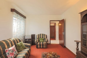 Uma sala de estar com sofá, poltrona e uma mesinha com objetos decorativos.