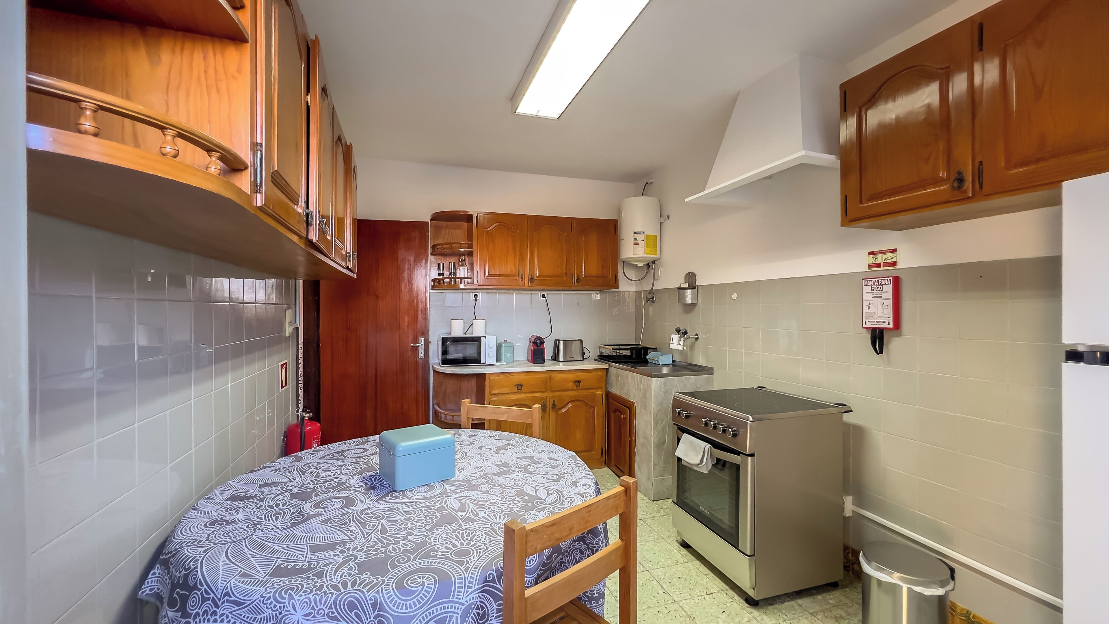 A compact kitchen with wooden cabinets, a microwave, a toaster, and a stove.