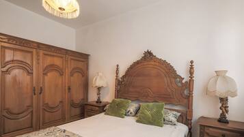 A bedroom with a wooden bed, a nightstand, a lamp, and a wardrobe.