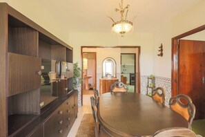 Ein Essbereich mit Holztisch, Stühlen, einer Kandelaber und einer Küche im Hintergrund.