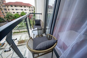 A balcony with wicker chairs and a glass table, overlooking a cityscape. - Cozy&stlyish  1-bedroom apartment in Riara One Residency Lavington Nairobi (Nairobi)