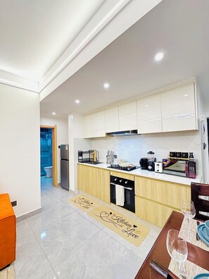 A modern kitchen with white cabinets, a built-in oven, and a microwave. - Cozy&stlyish  1-bedroom apartment in Riara One Residency Lavington Nairobi (Nairobi)