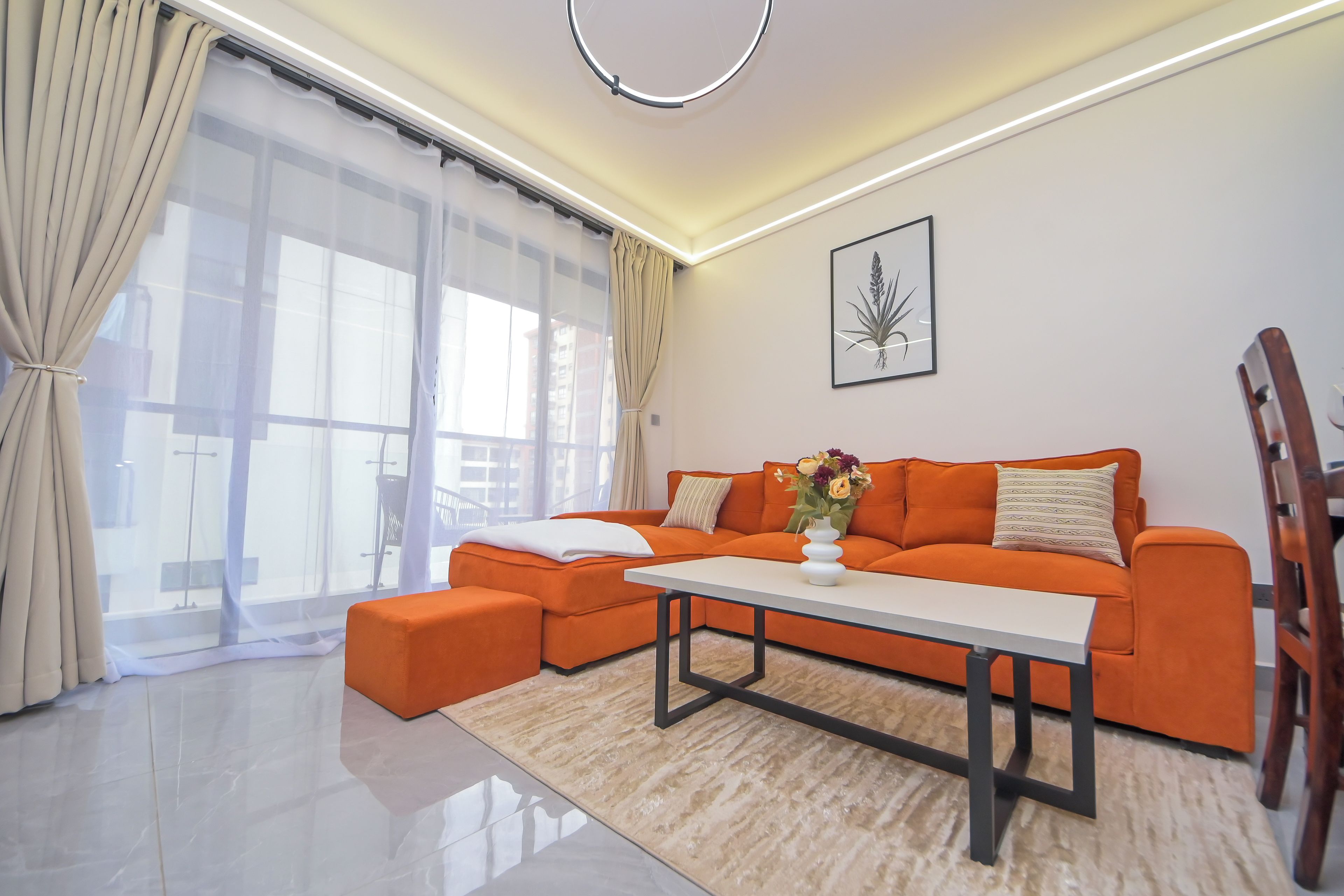 A modern living room with a sectional sofa, a coffee table, and a large window with curtains.