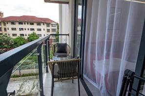 A balcony with a wicker chair, a small table, and a sheer curtain. - Cozy&stlyish  1-bedroom apartment in Riara One Residency Lavington Nairobi (Nairobi)