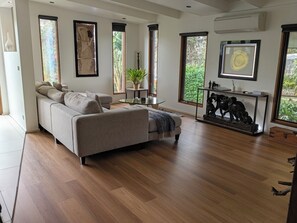 A modern living room with a sofa, a glass coffee table, and a sculpture on a console table.