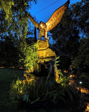 A bird sculpture on a rock with surrounding vegetation.