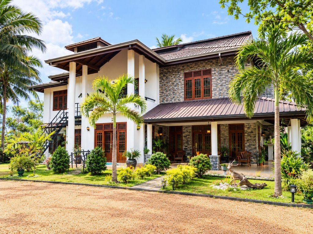 A two-story house with a stone facade, wooden columns, and a covered porch.