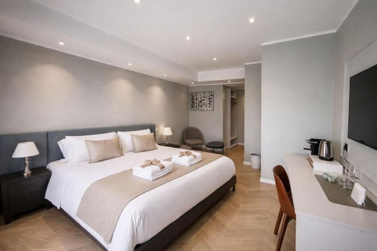 Una habitació d'hotel amb un llit, taules de nit, un escriptori i una cadira.