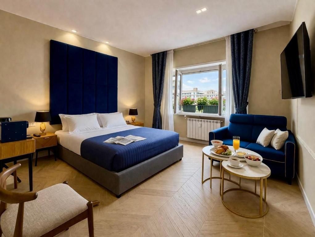 A hotel room with a bed, a sofa, a dining table with breakfast, and a window with curtains.