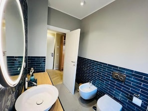 Un bany amb un mirall gran, un rentapel, un vàter i un lavabo.