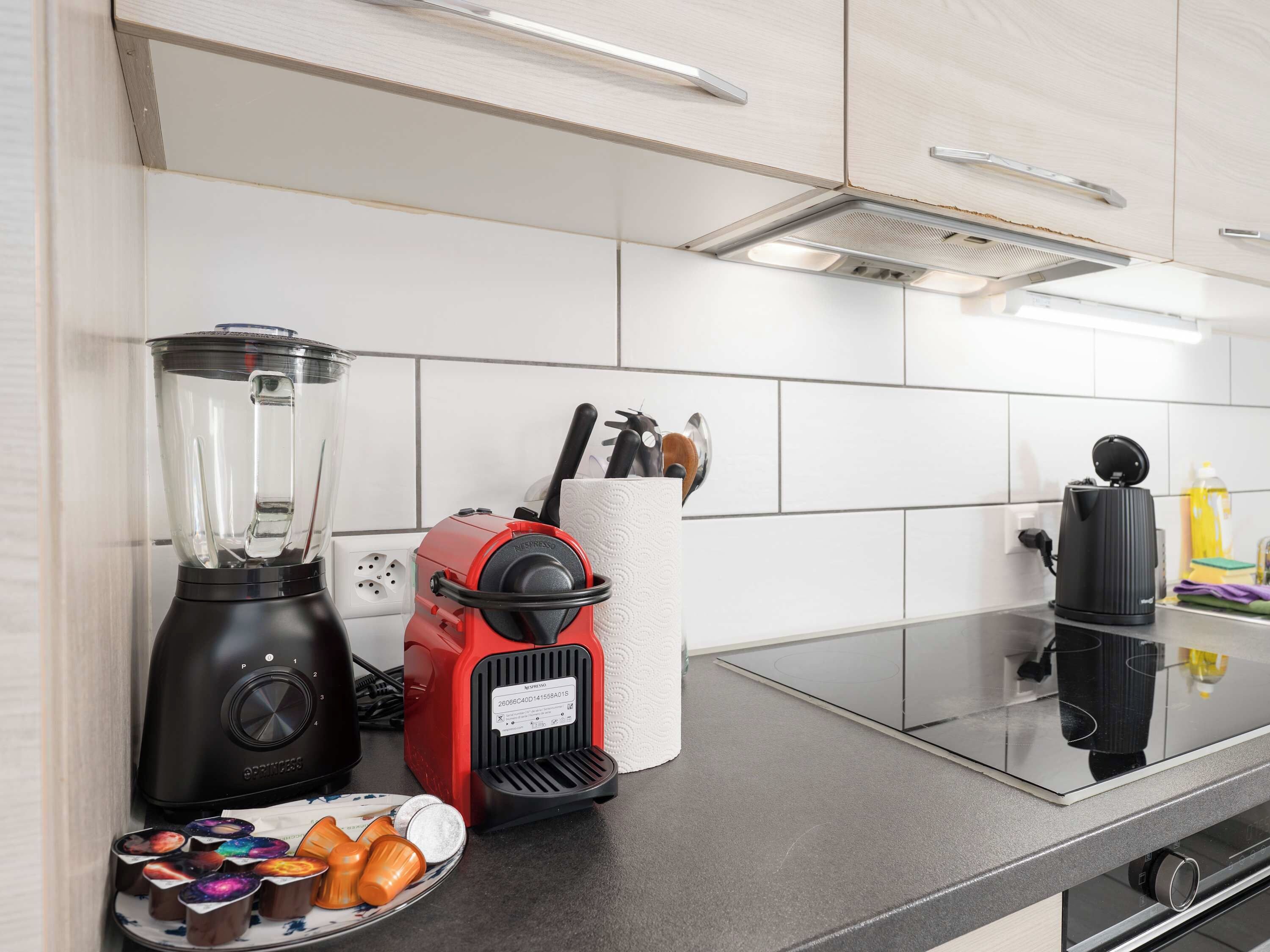 Kitchen with coffee machine, blender and cooking essentials.