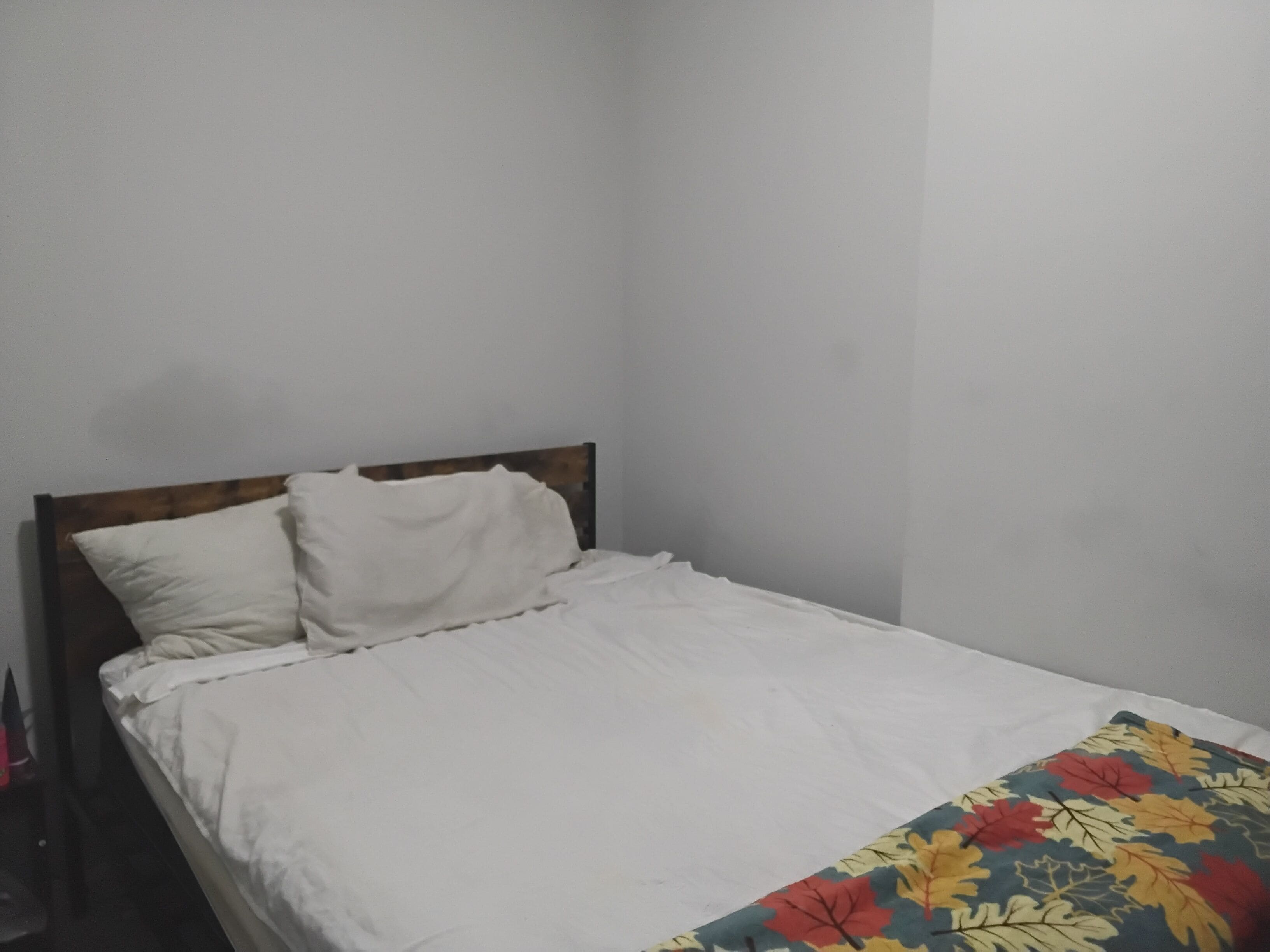 Una cama individual con cabecera de madera y ropa de cama blanca.