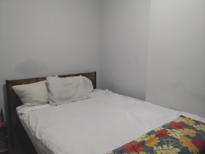Ein Einzelbett mit hölzernem Kopfteil und weißer Bettwäsche.
