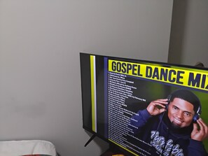 Uma televisão exibindo uma lista com o título 'GOSPEL DANCE MIX', apresentando títulos de músicas e artistas.
