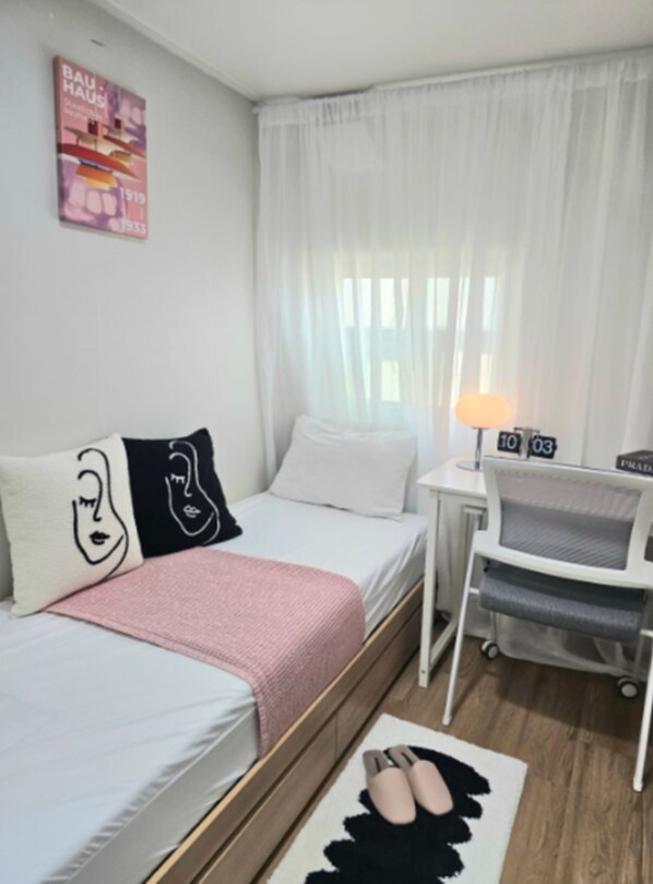 Une chambre d’hôtel avec un lit, un petit bureau, une chaise, une lampe et une affiche au mur.