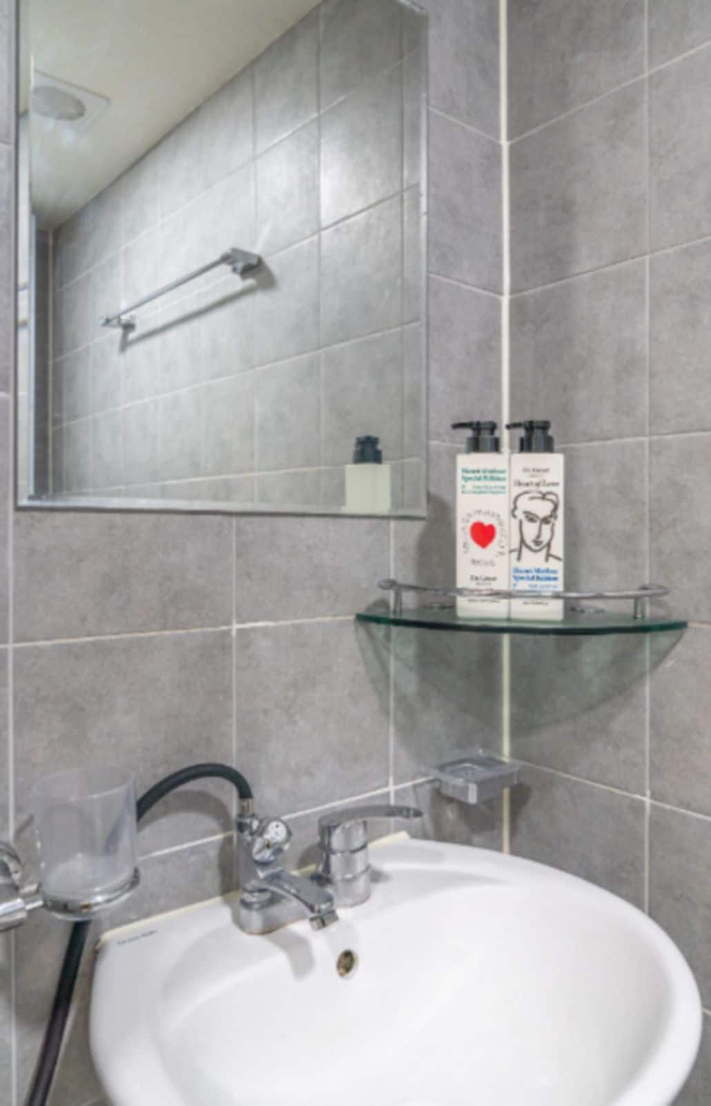 A bathroom with a white sink, a glass shelf, and a mirror.