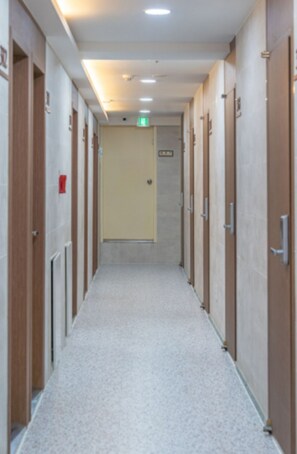 A hotel corridor with doors on both sides, a carpeted floor, and an exit sign on the wall. - 1-Min Walk to Shinnonhyeon Station - GANGNAM Lovely Studio - #Modern #Travel (Seoul)