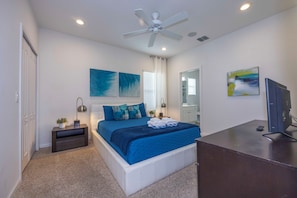 A bedroom with a bed, bedside tables, a desk, a ceiling fan, and artwork on the walls. - Private Pool Near Disney with Game Room (Kissimmee)