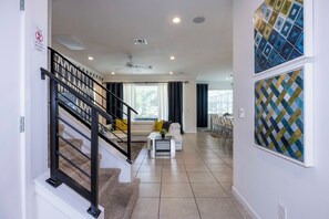 A modern living room with a staircase, a dining area, and a view of the outdoors. - Private Pool Near Disney with Game Room (Kissimmee)