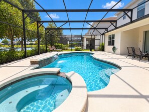 A swimming pool with a sunken hot tub, surrounded by lounge chairs and a covered patio area. - Bella Vida 5BR Pool Home with Game Room & Loft (Kissimmee)