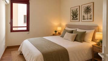 Ein Schlafzimmer mit einem Bett, Nachttischlampen, einem Fenster mit Blick und zwei Wandbildern von Pflanzen.