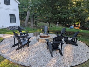 Un espace extérieur aménagé avec des chaises Adirondack et un foyer en pierre.