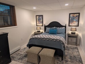 Une chambre à coucher comprenant un lit, deux tables de chevet, une commode et des œuvres d’art accrochées aux murs.
