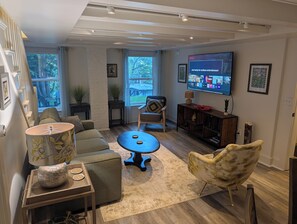 Un salon moderne comprenant un canapé, un fauteuil, une table basse et un téléviseur à écran plat fixé au mur.