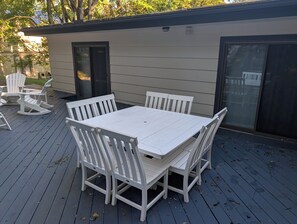A deck with a white table and chairs, a rocking chair, and a sliding glass door. - NEW!  The Deer and Birches Combination - 2 Beautiful Houses on the Same Property! (Frankfort)