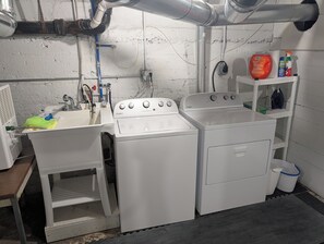 A laundry room with a sink, two washers, and a shelf with cleaning supplies. - NEW!  The Deer and Birches Combination - 2 Beautiful Houses on the Same Property! (Frankfort)