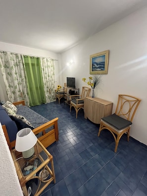 Ein Zimmer mit einem Bett, einem Schreibtisch, einem Stuhl, einer Lampe und einem Bild an der Wand.