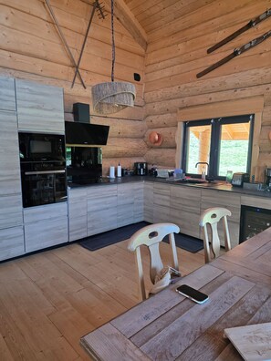 Une cuisine moderne avec des meubles en bois, un four encastré et un coin repas comprenant une table et des chaises.