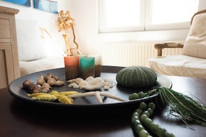 Una mesa redonda con diversos objetos, entre ellos conchas marinas, un cactus y una planta.