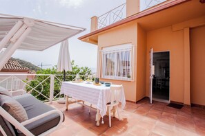 Een balkon met een eettafel, een stoel en een bank.