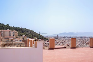 Una terraza en la azotea con vistas a un paisaje urbano y montañas al fondo.