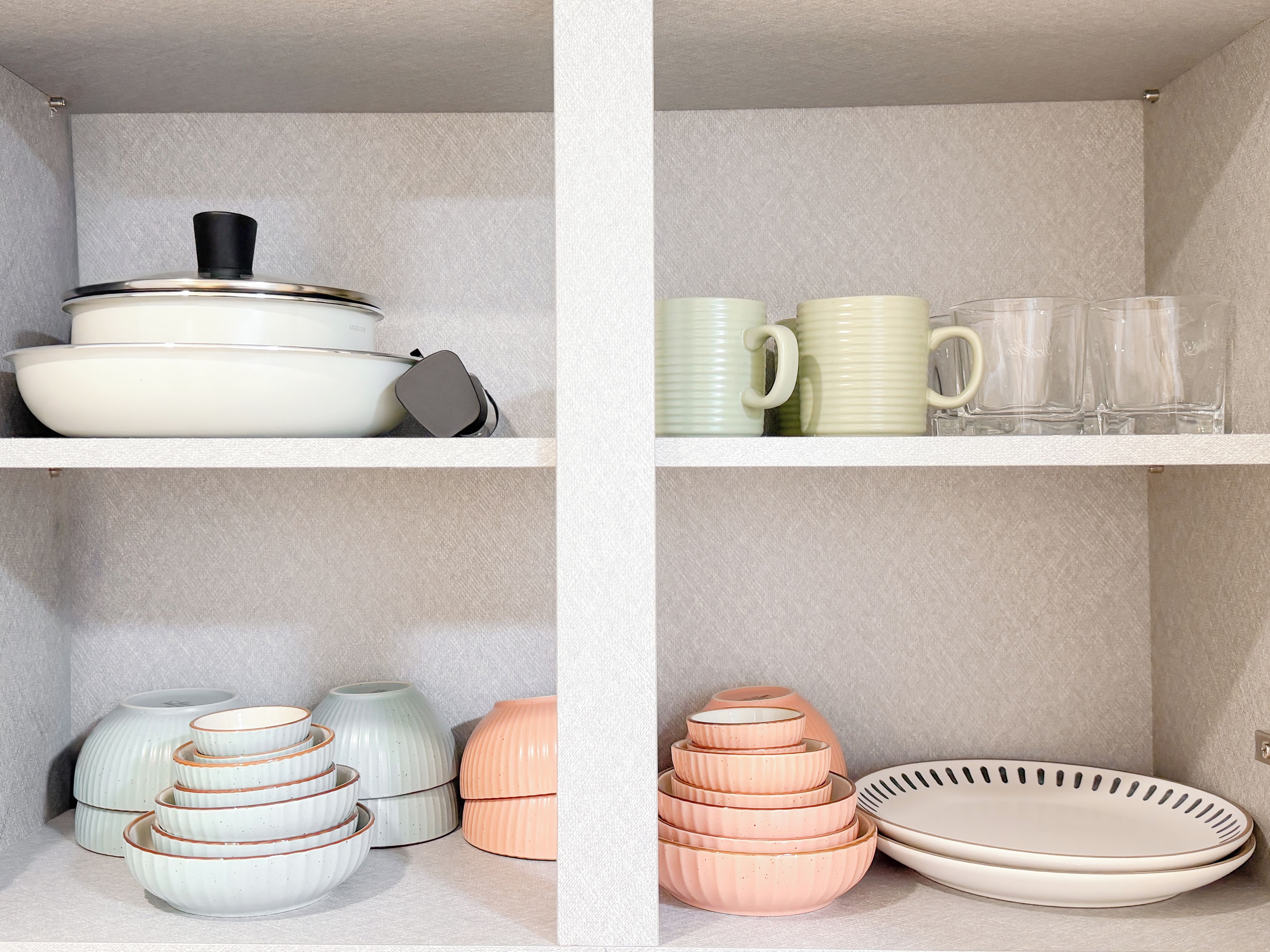 A kitchen with white cabinets and a variety of dishes and cookware.