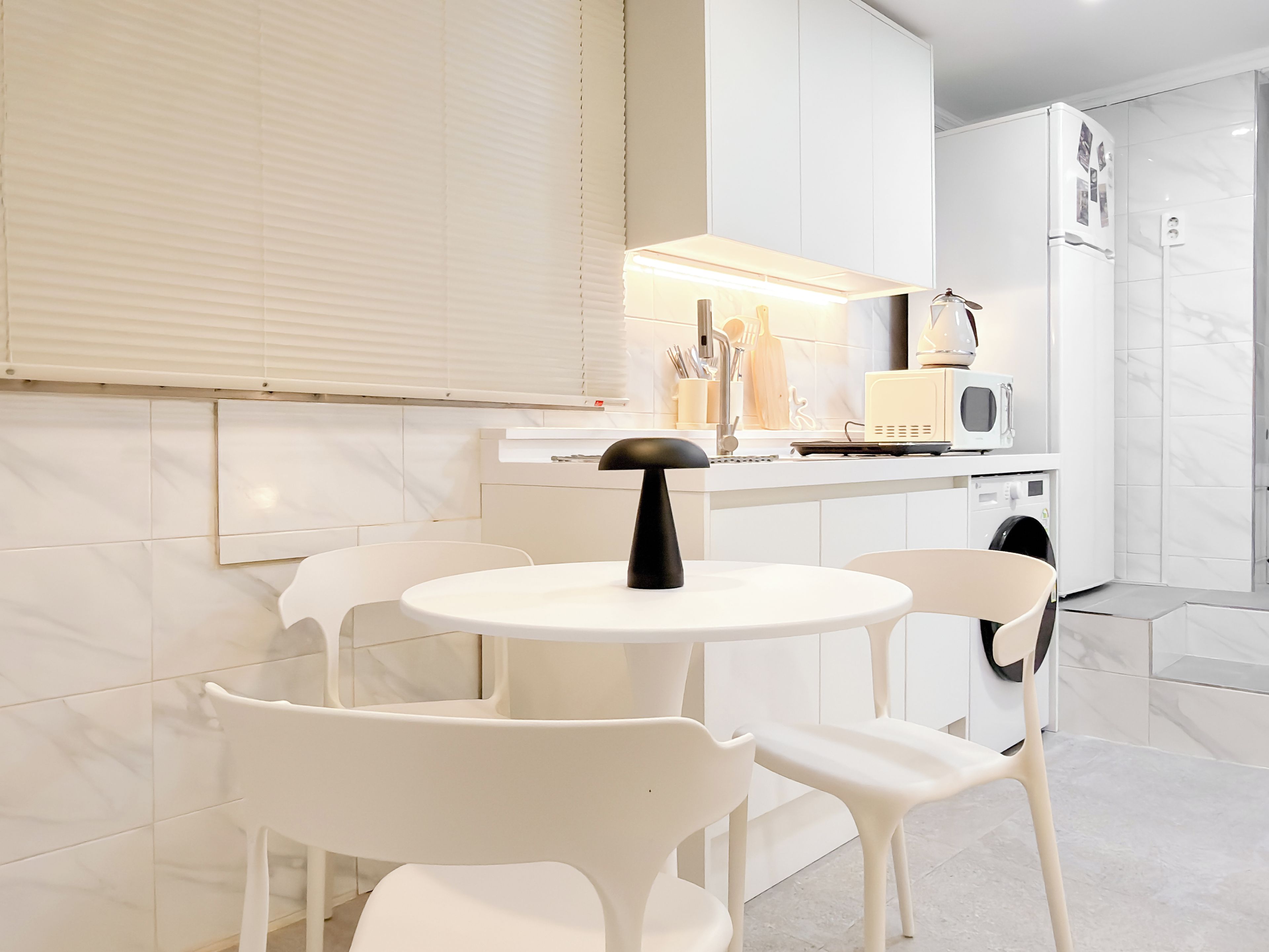 A modern kitchen with white cabinetry, a round table, and two chairs.