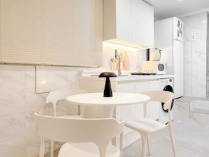 Una cocina moderna con armarios blancos, una mesa redonda y dos sillas.